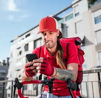 Freelance courier using a smartphone while resting on his bicycle in an urban setting