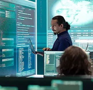 Engineer analysing complex digital interfaces on large screens in a secure tech environmet.