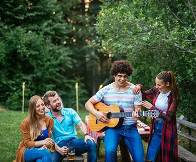 Friends playing guitar and laughing together outdoors, celebrating authentic connection and shared joy.